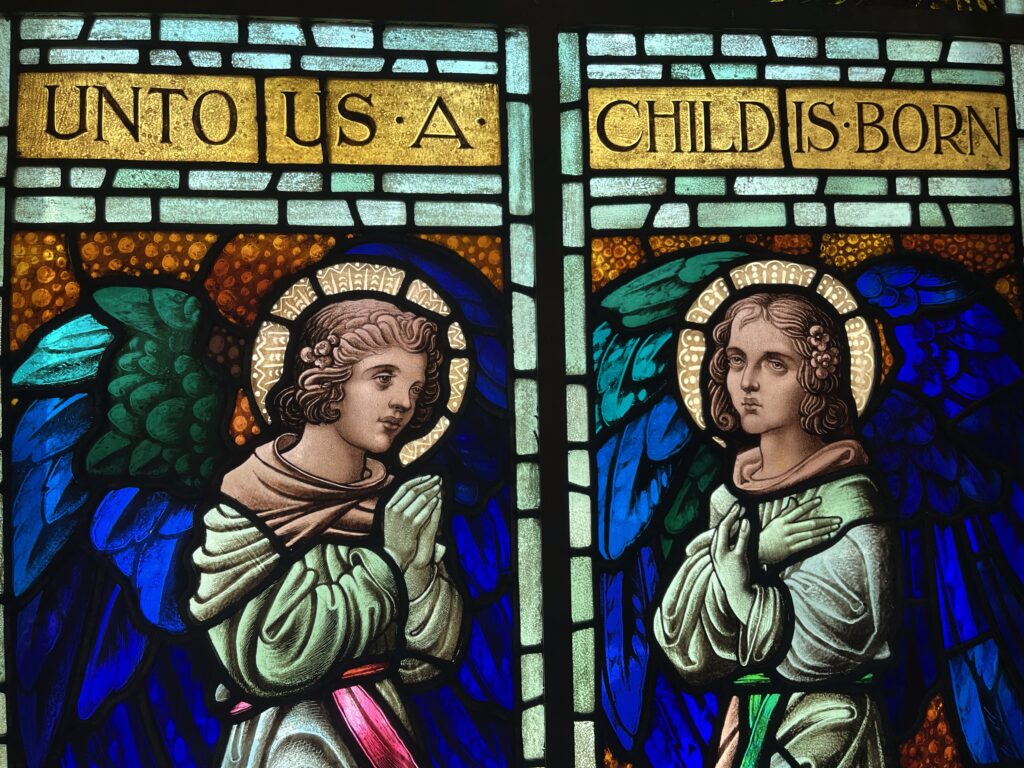 Cathedral window of angels and the words Unto Us a Child is Born.